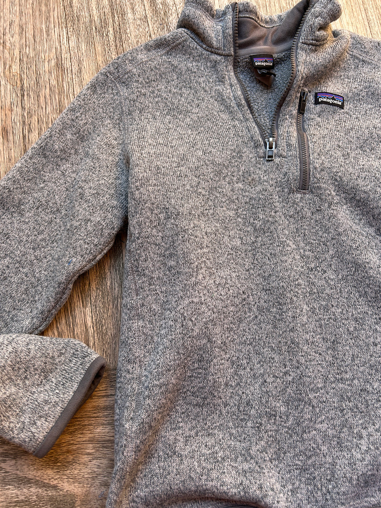 Gray fleece pullover with brand logo on a wooden surface