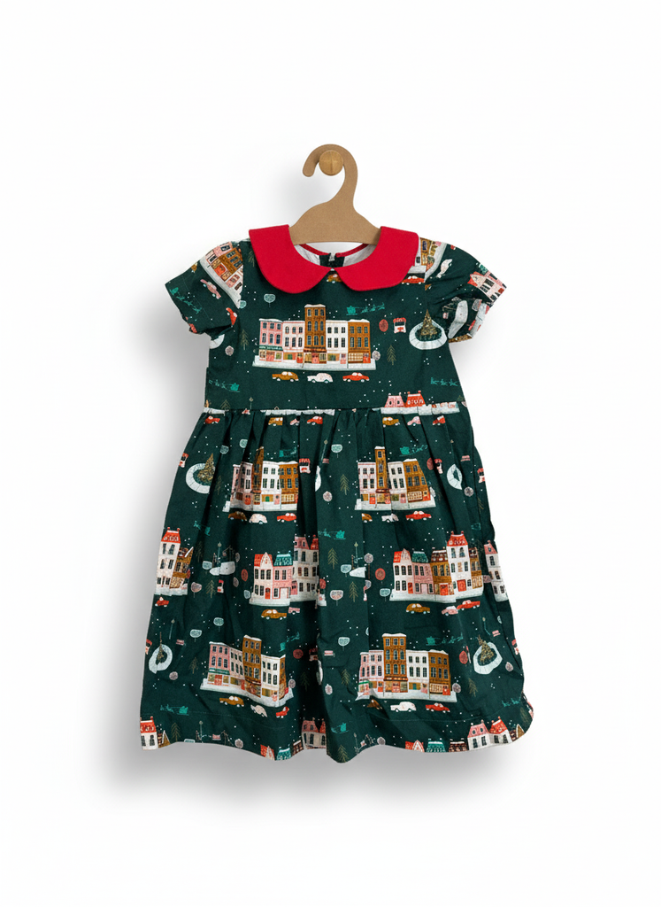Children's dress with cityscape print and red collar on a hanger