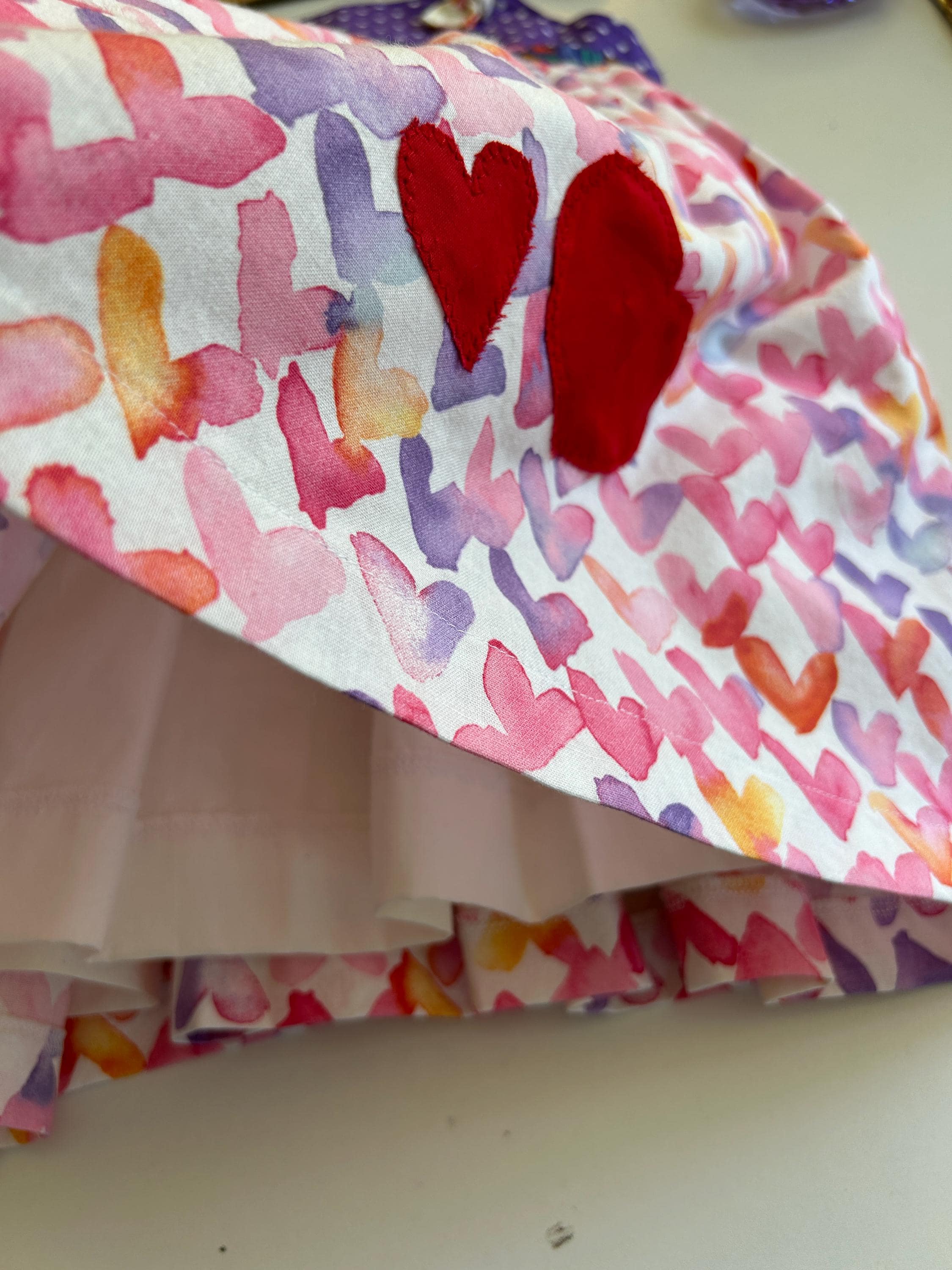 Colorful fabric with heart patterns and two red hearts on a white surface