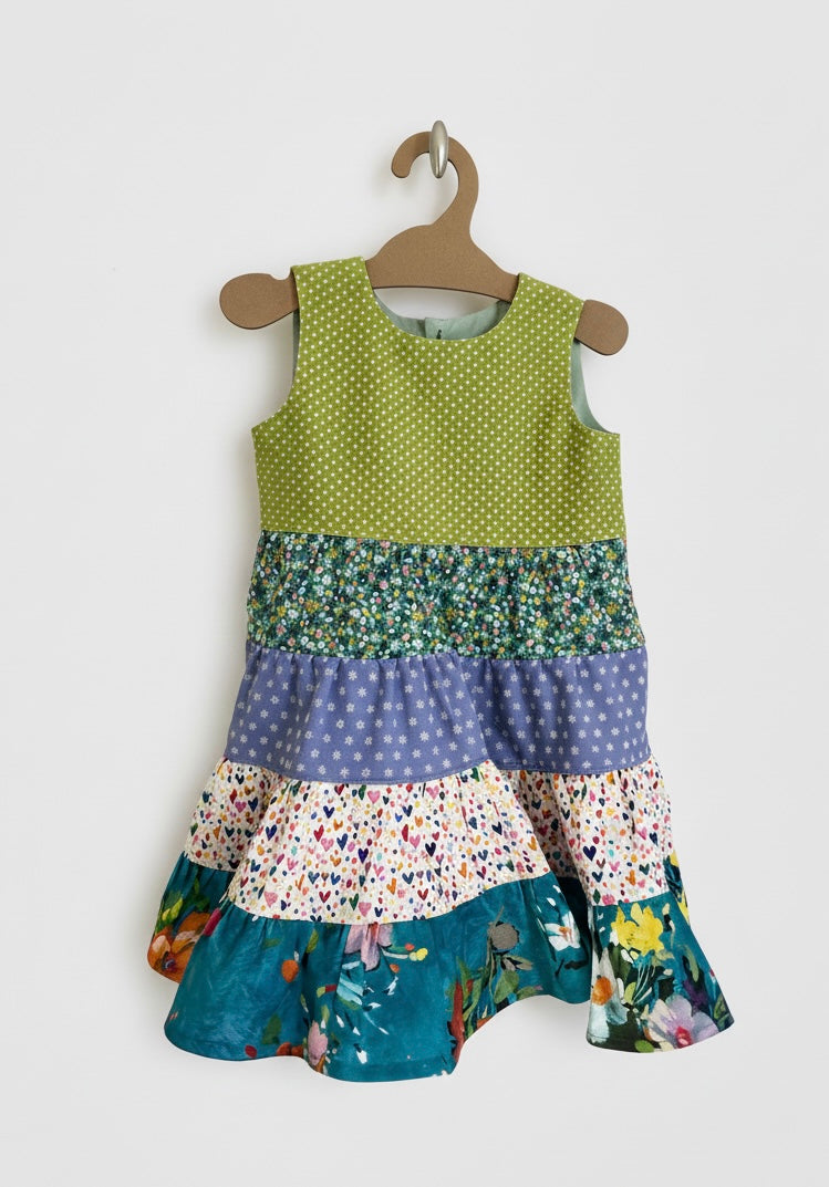 Colorful tiered dress on a hanger against a white background