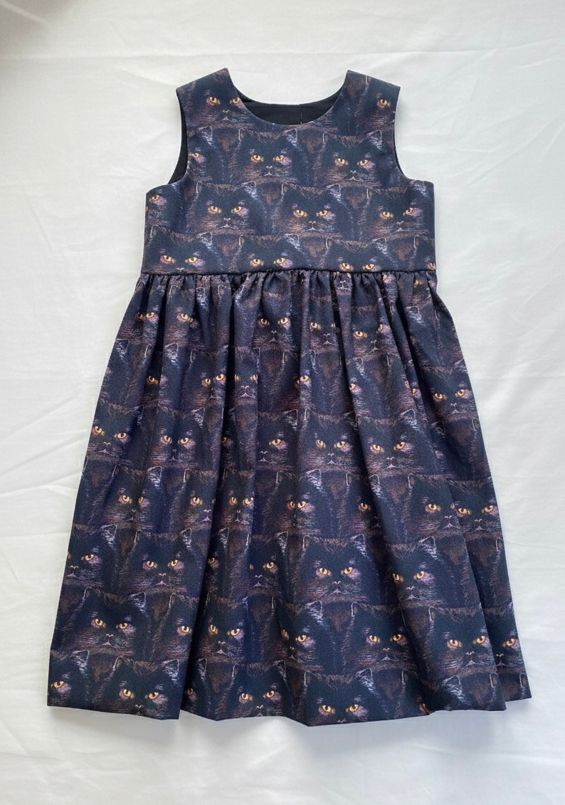 Black cat dress with cat pattern with gold eyes on a white background