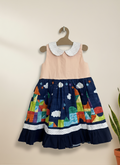 Children's dress with colorful skirt and beige top on a hanger against a beige wall.