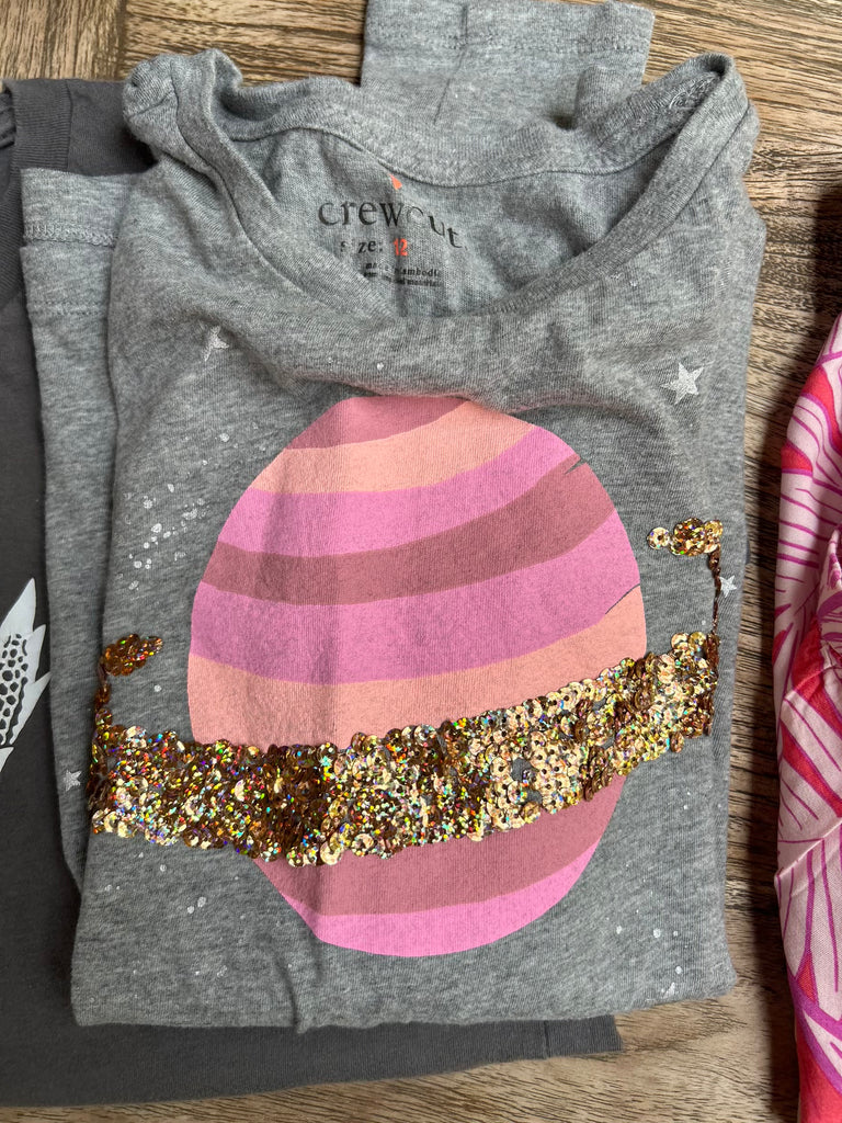 Folded gray hoodie with a colorful egg design on a wooden surface