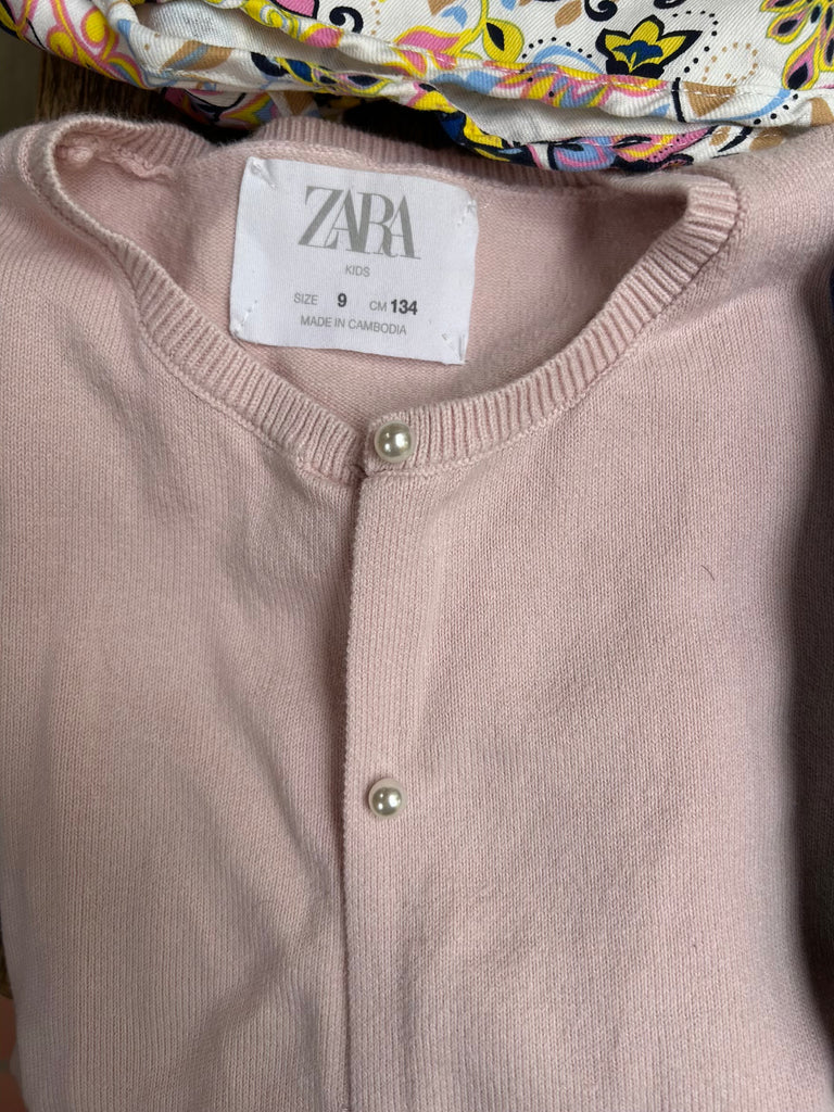 Close-up of a pink cardigan with a Zara label on a colorful background