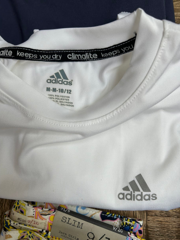 White Adidas shirt with visible branding and text on a wooden surface