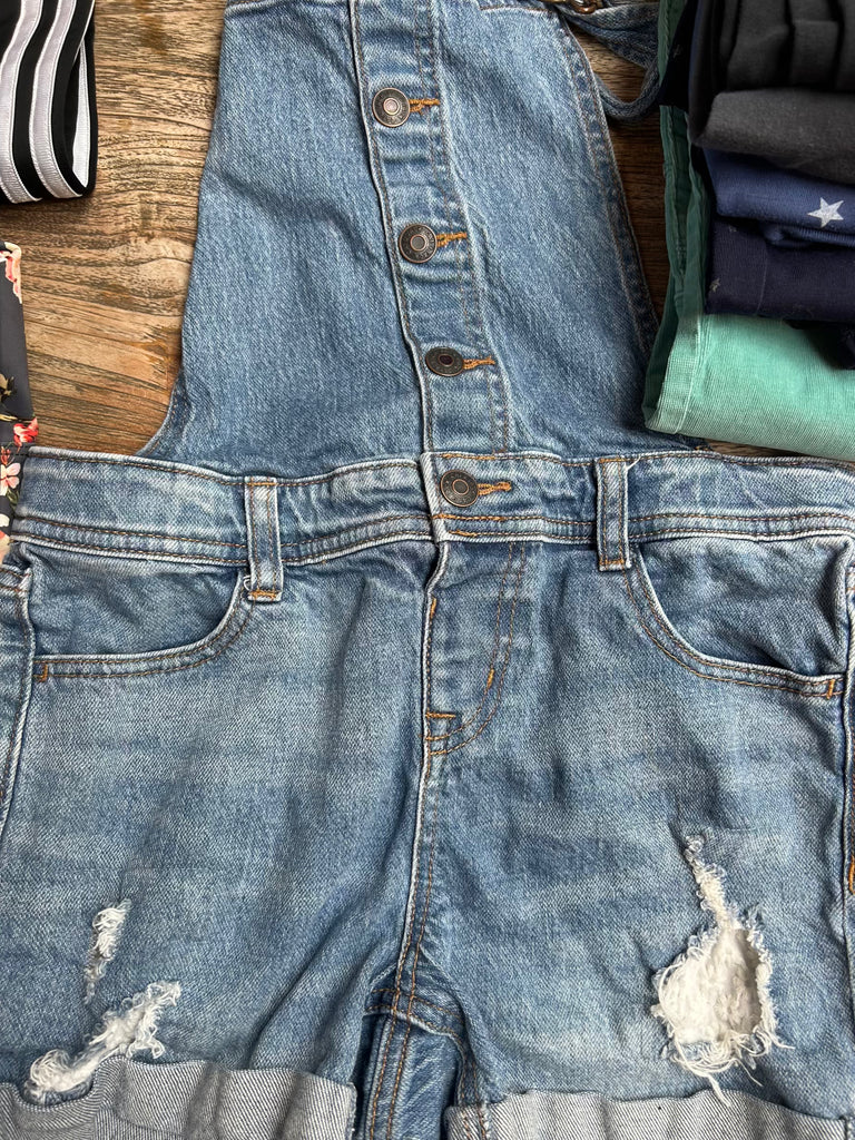 Denim romper with distressed details on a wooden surface