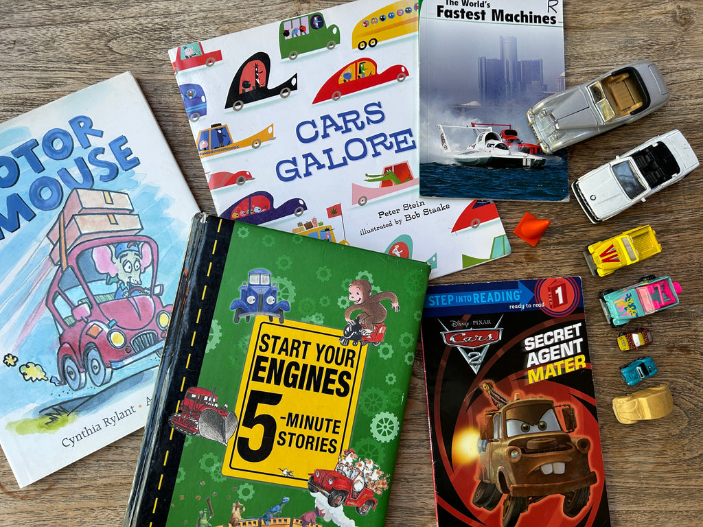 Children's books and toy cars on a wooden surface