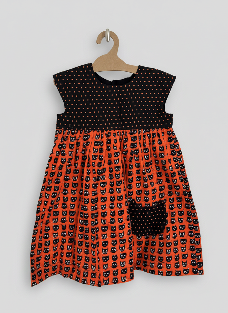 Dress with black cat pattern on orange background, hanging on a gray background