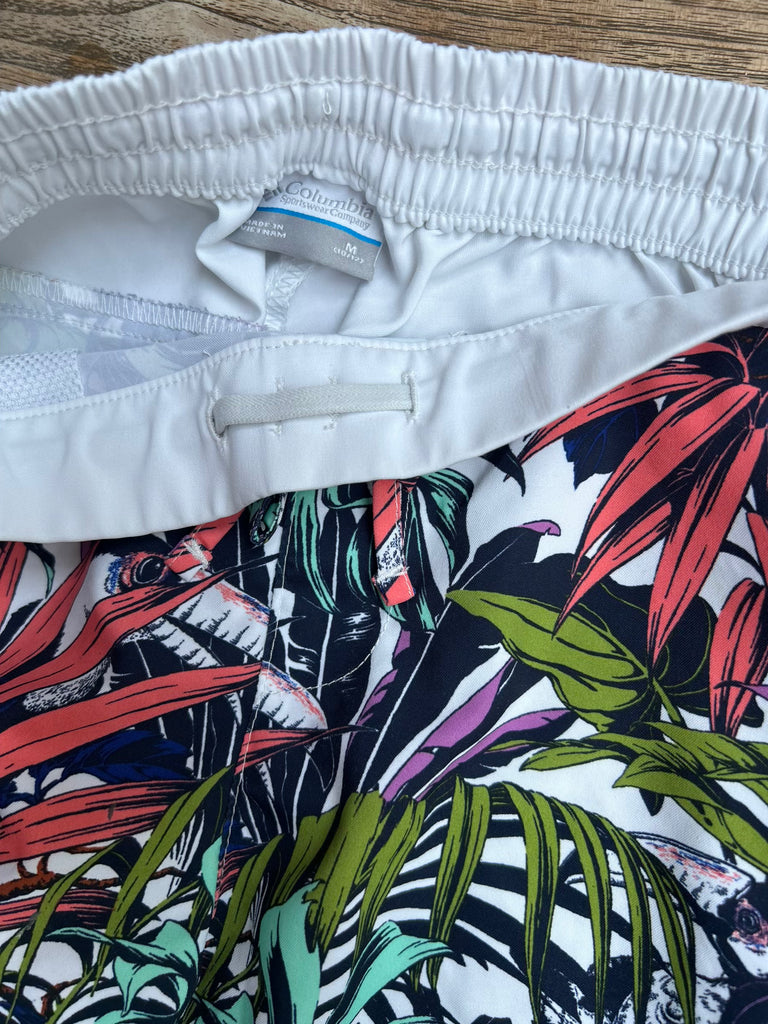 White shorts with a colorful tropical pattern on a wooden surface