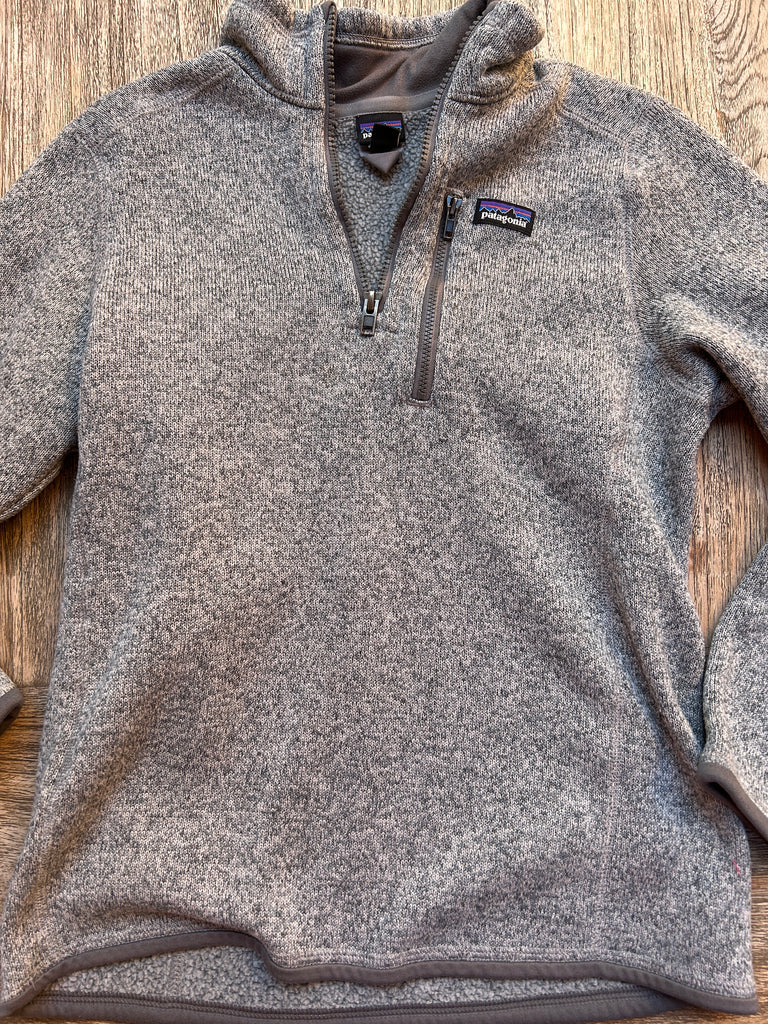 Gray fleece pullover with a brand logo on a wooden surface