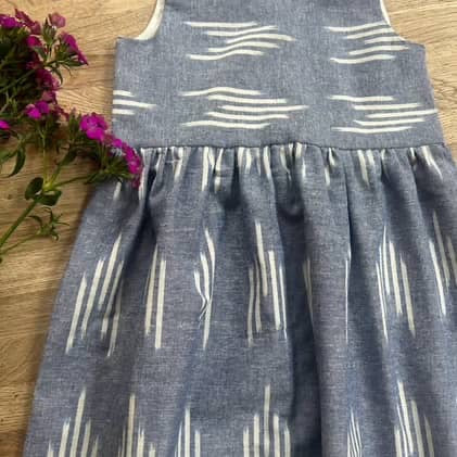 Gray dress with white pattern on a wooden surface with pink flowers.