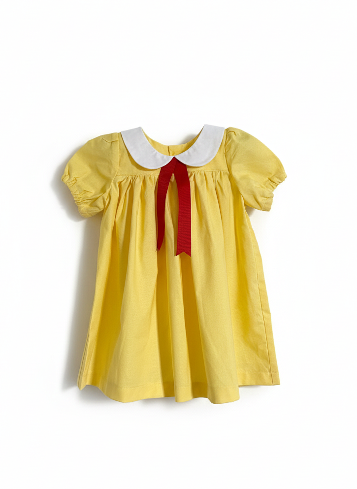 Yellow dress with a white collar and red ribbon on a white background