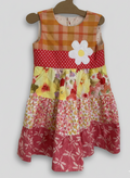 Colorful patchwork dress with floral patterns on a hanger against a white background