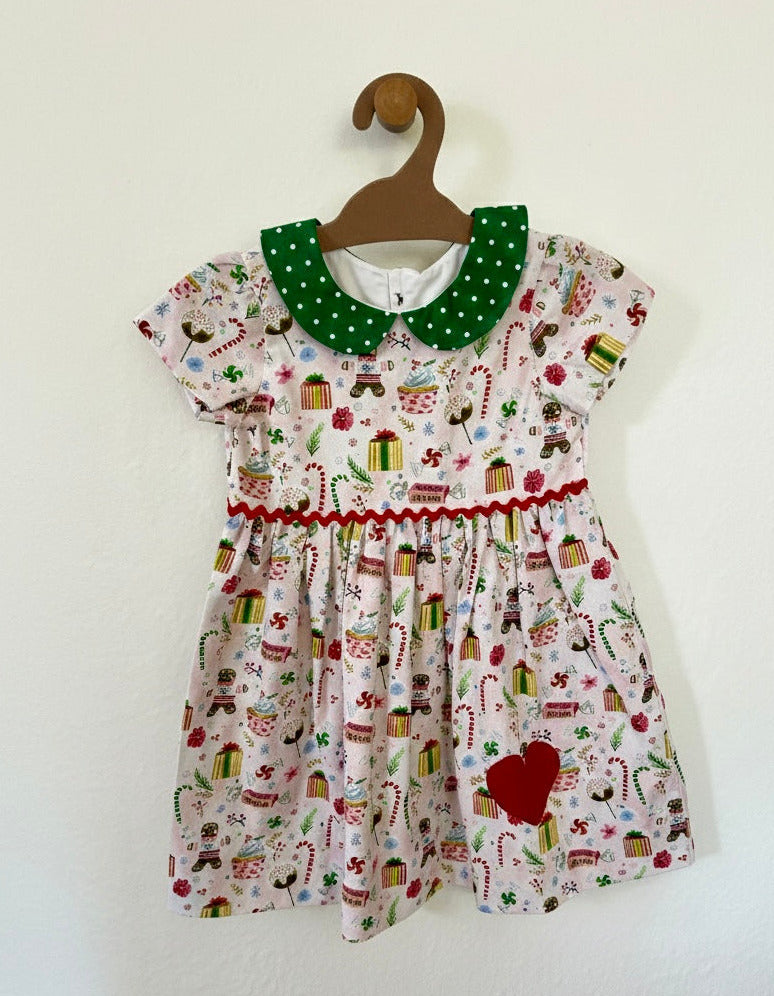 Children's dress with Christmas-themed print on a hanger against a white background