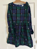 Navy and green plaid dress with butterfly patterns on a hanger against a white door.