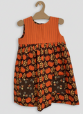 Children's dress with pumpkin pattern on a hanger against a white background