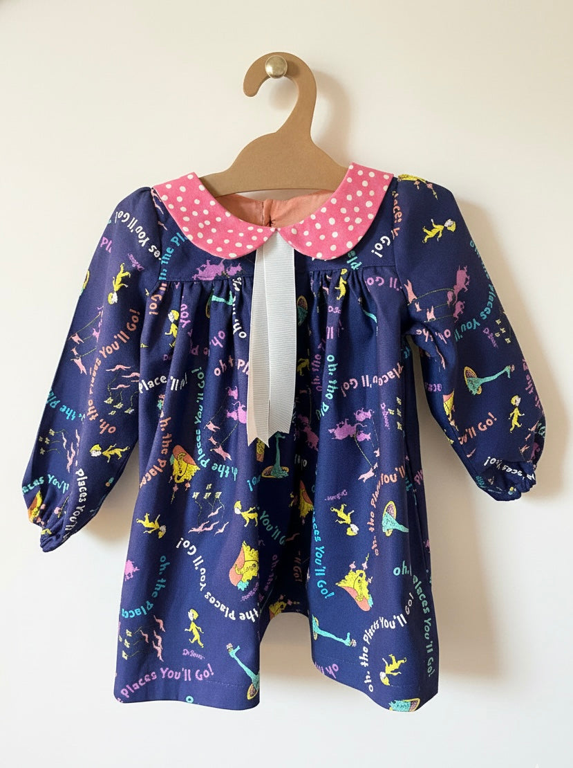 Children's dress with colorful pattern on a hanger against a white background