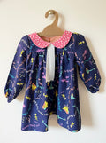 Children's dress with colorful pattern on a hanger against a white background
