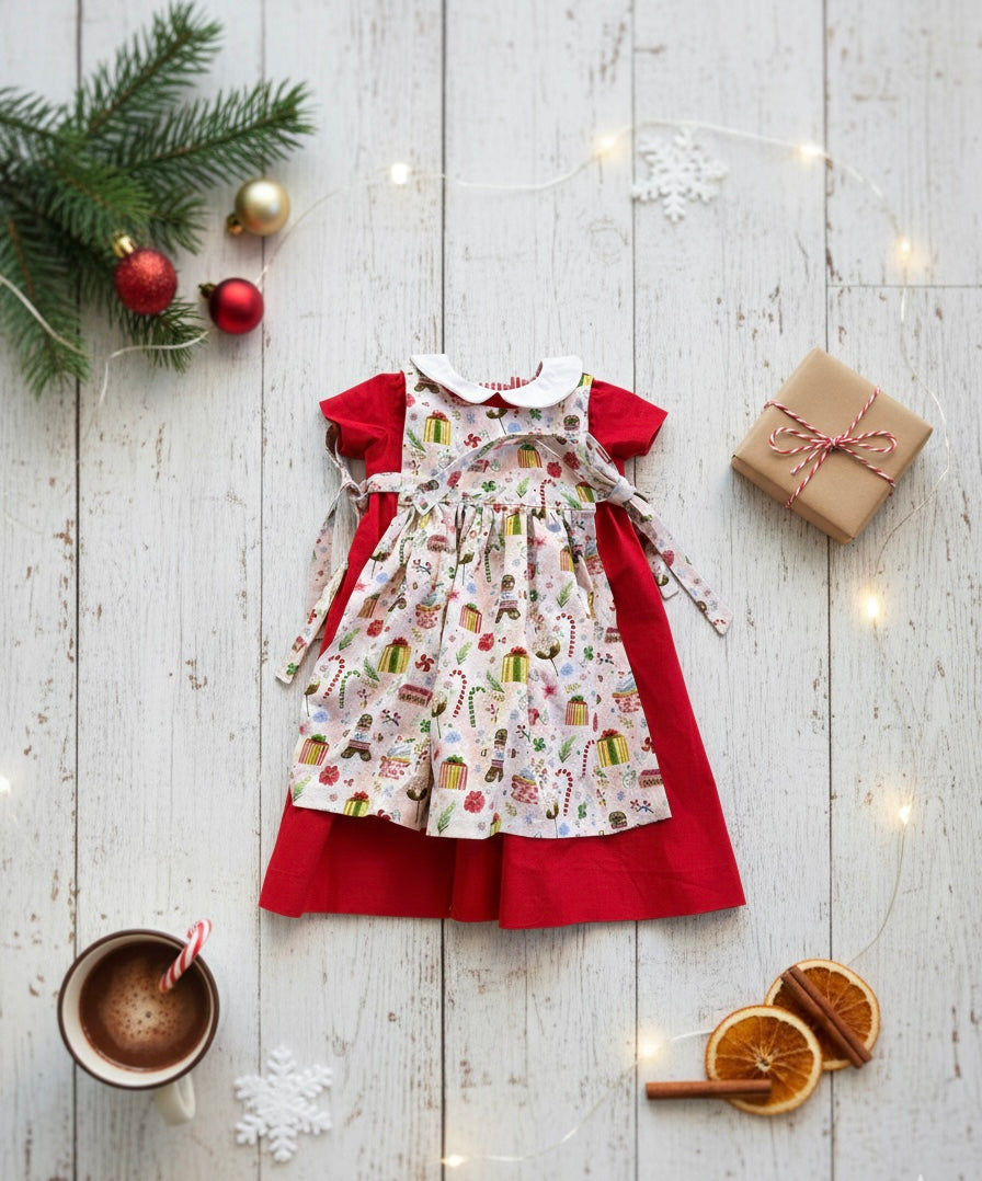 Children's dress with red skirt and patterned top on a wooden surface with Christmas decorations.