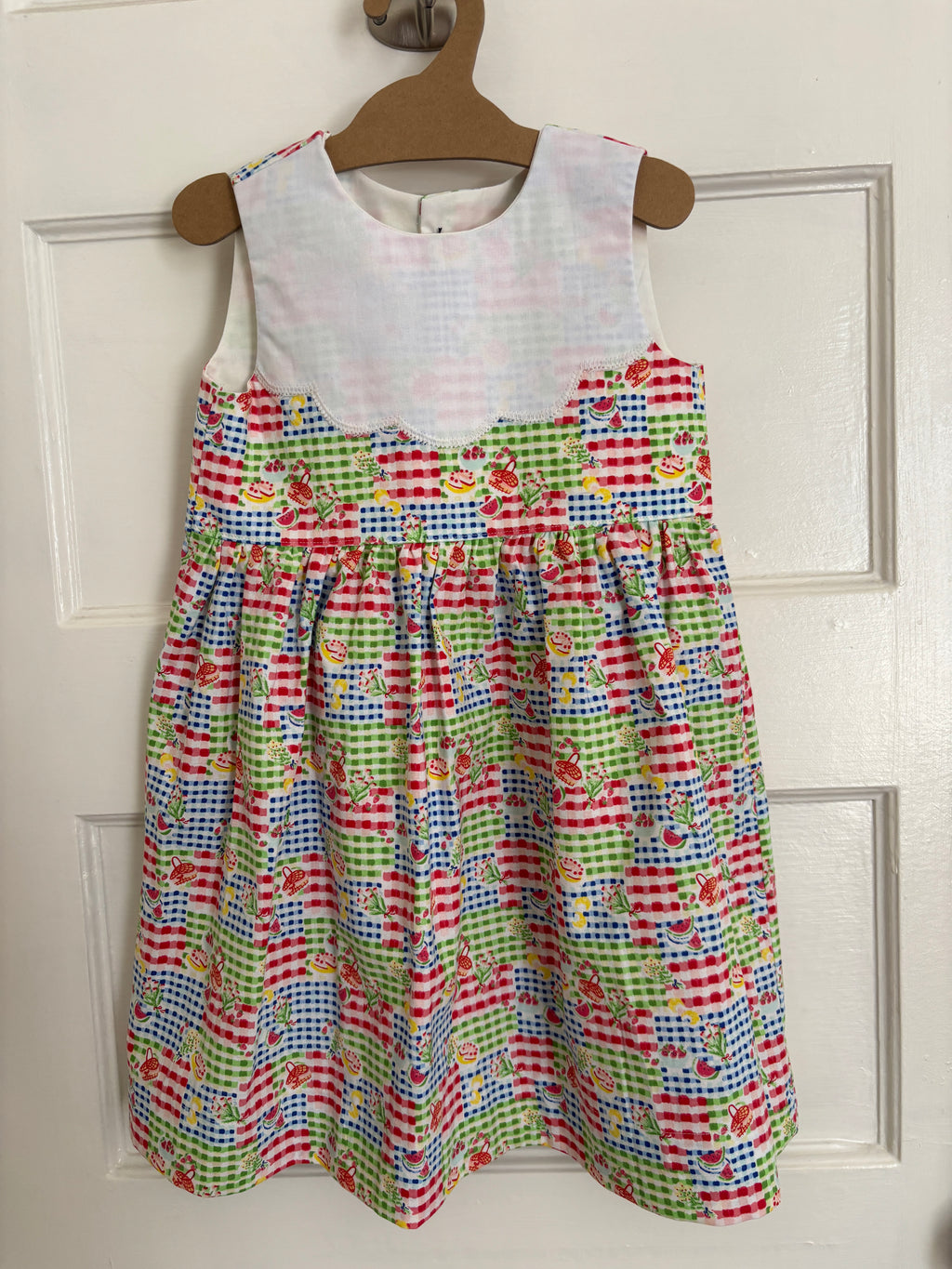 Colorful patterned dress on a hanger against a white door background