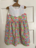 Colorful patterned dress on a hanger against a white door background