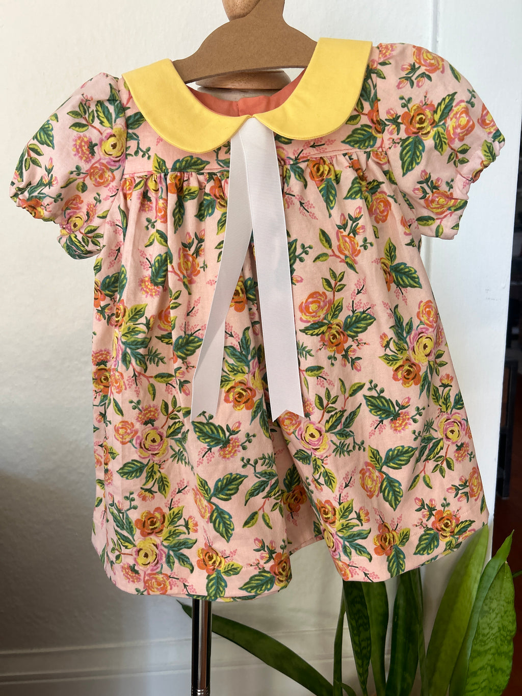 Floral dress on a hanger with a plant in the background