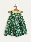 Green dress with sloth pattern and yellow collar on a hanger against a white background