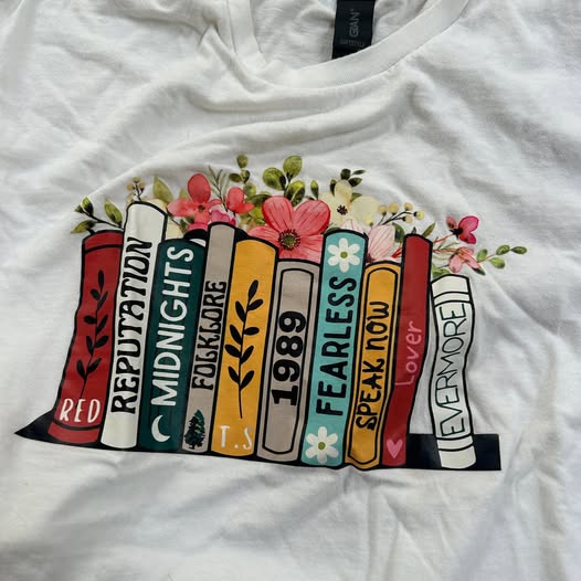 White t-shirt with colorful book graphic and text on a white background