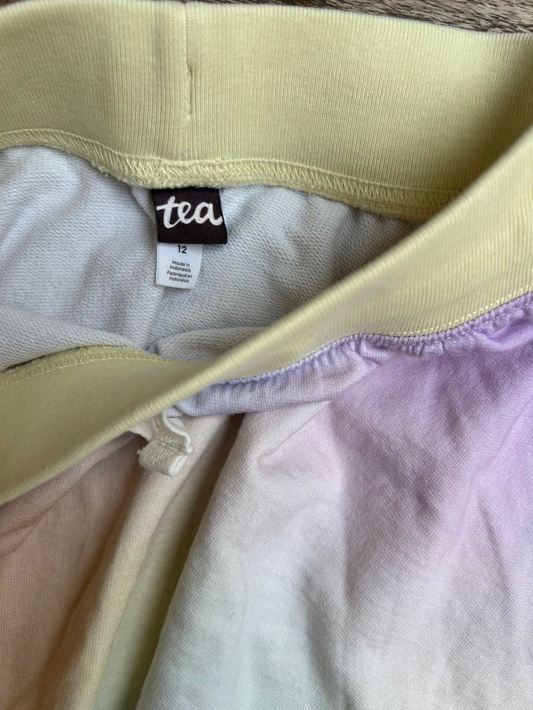 Close-up of a garment with a 'tea' brand tag on a neutral background