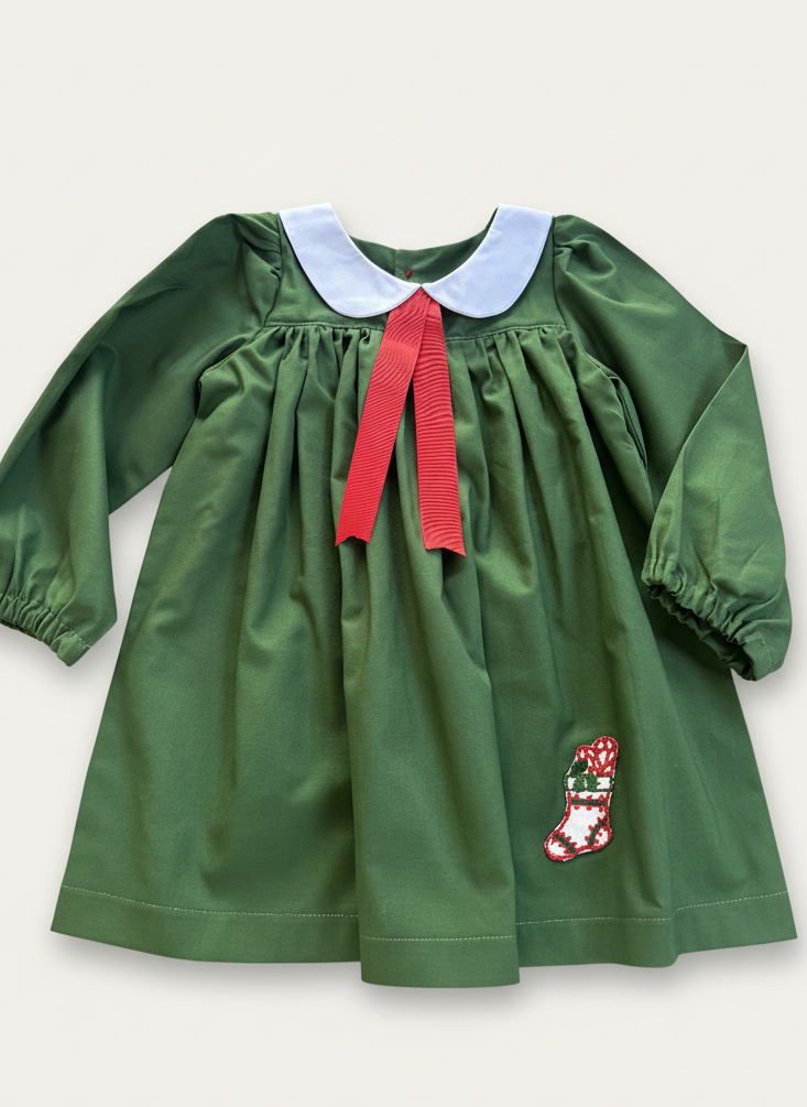 Green dress with red ribbon and white collar on a light gray background