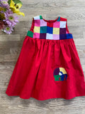 A colorful sleeveless patchwork dress for toddlers, featuring a red gathered skirt, a patchwork bodice with contrasting colors, and an appliquéd elephant on the front.